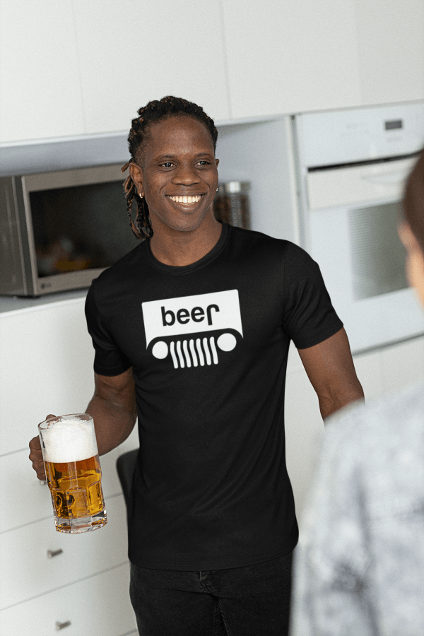 Smiling man holding a beer in the kitchen wearing Jeep logo beer shirt