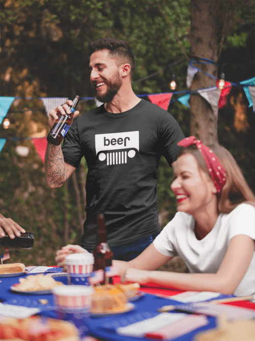 Tattooed man wearing a Jeep Beer Shirt drinking a beer at a 4th of July BBQ party