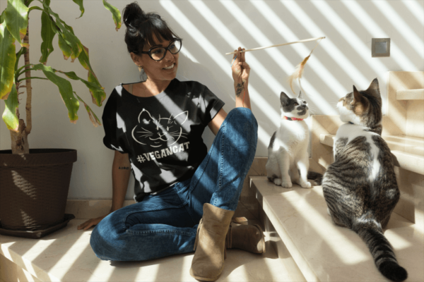 woman playing with her cats wearing a VeganCat shirt