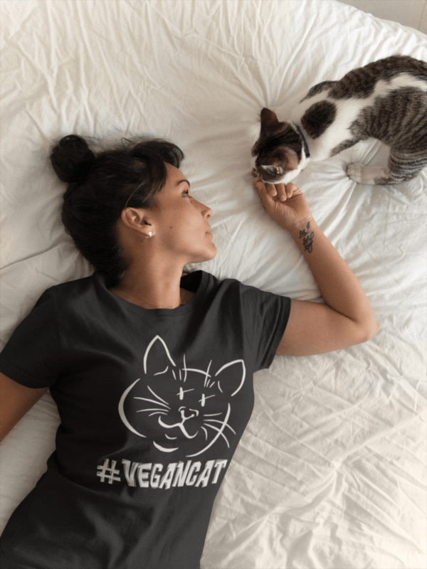 Girl wearing a #vegancat t-shirt petting her cat on the bed